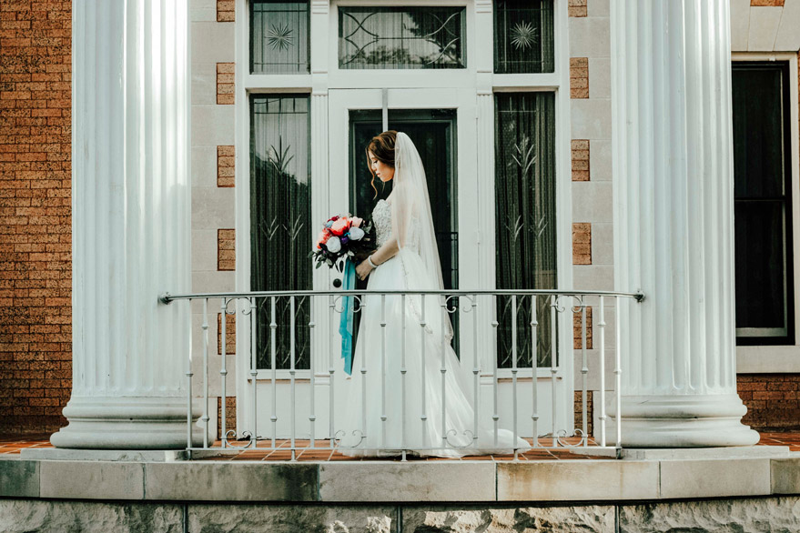 A beautiful bride stands in front of the art deco glass door at the Frank Phillips Mansion