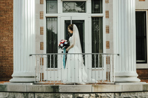 A beautiful bride stands in front of the art deco glass door at the Frank Phillips Mansion