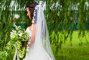 A bride stands beneath a willow tree in the Frank Phillips Mansion Lawn