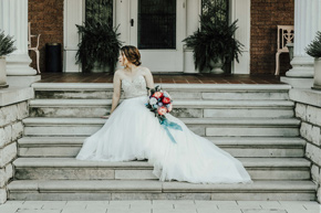 A beautiful bride sits on the front steps of the Frank Phillips Mansion