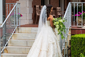 A bride stands on the front steps of the Frank Phillips Mansion